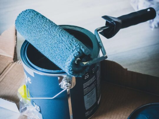 paint roller covered in blue paint sitting on paint can